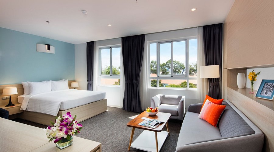 Interior of a modern serviced apartment in Ho Chi Minh City with a bedroom, living area, sofa, and large windows — the type of furnished housing foreigners can rent in Vietnam