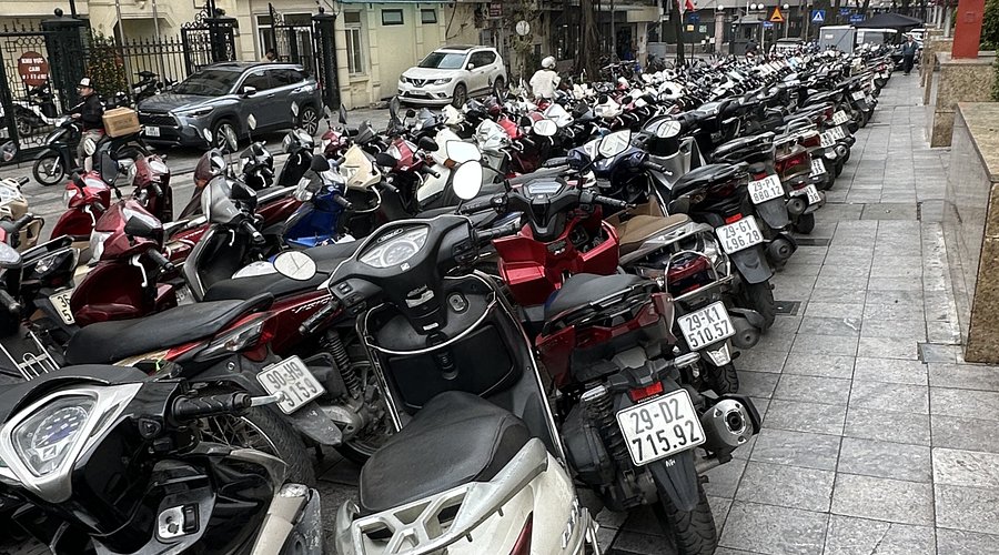 Vietnamese sidewalk filled with parked motorbikes in front of shops