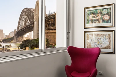 A magenta Egg chair framing the Sydney Harbour Bridge through the window