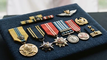 Realistic illustration of the military medals and badges awarded to Omar Dhani, including Bintang Swa Bhuwana Paksa, Bintang Jalasena, Bintang Yudha Dharma, Satyalancana Santi Dharma, Satyalancana Seroja, shown against a light Indonesia flag background. AI-generated illustration, not an authentic photograph.