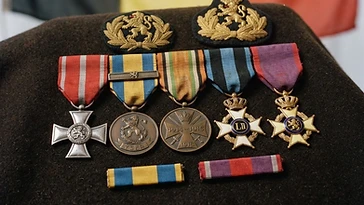 Realistic illustration of the military medals and badges awarded to Gaston Braun, including Military Decoration for Exceptional Service or Acts of Courage or Devotion, Yser Medal, Commemorative Medal of the 1914–1918 War, Order of Leopold II, Order of the Crown, shown against a light Belgium flag background. AI-generated illustration, not an authentic photograph.