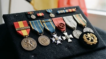 Realistic illustration of the military medals and badges awarded to Albert Lilar, including Commemorative Medal of the 1940–1945 War, Commemorative Medal for Foreign Operations or Missions, shown against a light Belgium flag background. AI-generated illustration, not an authentic photograph.