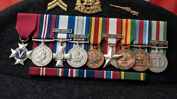 Realistic illustration of the military medals and badges awarded to Marc Dicaire, including Meritorious Service Medal, Canadian Forces' Decoration, Meritorious Service Cross, Canadian Volunteer Service Medal, General Campaign Star, Canadian Korea Medal, Sacrifice Medal, Medal of Military Valour, Star of Military Valour, shown against a light Canada flag background. AI-generated illustration, not an authentic photograph.