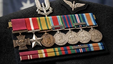 Realistic illustration of the military medals and badges awarded to Ben Roberts-Smith, including Victoria Cross for Australia, Star of Gallantry, Medal for Gallantry, Afghanistan Medal, Australian Active Service Medal, Australian Service Medal, Australian Defence Medal, shown against a light Australia flag background. AI-generated illustration, not an authentic photograph.