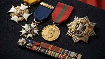 Realistic illustration of the military medals and badges awarded to Salgueiro Maia, including Grand Cross of the Order of Liberty, Grand Officer of the Military Order of the Tower and of the Sword, Gold Medal of the city of Santarém, shown against a light Portugal flag background. AI-generated illustration, not an authentic photograph.