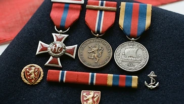 Realistic illustration of the military medals and badges awarded to Erik Bye, including King Haakon VII Freedom Cross, National Service Medal, Armed Forces Medal for Heroic Deeds, shown against a light Norway flag background. AI-generated illustration, not an authentic photograph.