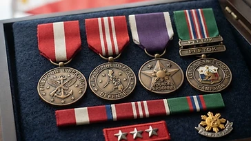 Realistic illustration of the military medals and badges awarded to Eulogio Balao, including Philippine Liberation Medal, Philippine Defense Medal, Wounded Personnel Medal, Anti-Dissidence Campaign Medal, shown against a light Philippines flag background. AI-generated illustration, not an authentic photograph.