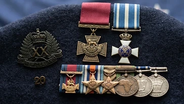 Realistic illustration of the military medals and badges awarded to Charles Upham, including Victoria Cross and Bar, Order of Honour (Greece), shown against a light New Zealand flag background. AI-generated illustration, not an authentic photograph.
