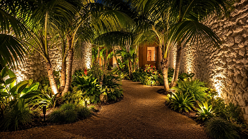 Stone-walled garden walkway with warm landscape lighting leading to a doorway in Santa Barbara