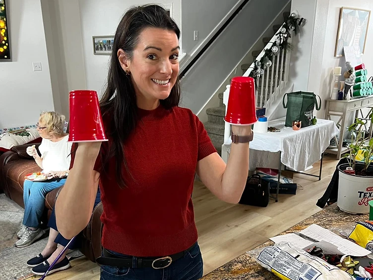 Ashley in her kitchen, raising two red cups