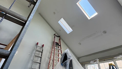 Vaulted Ceiling Interior — Two ladders, full floor protection, and a vaulted ceiling with skylights prepped for a flawless finish.
