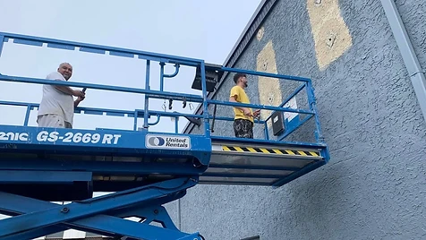 High-Reach Masonry — Patched and prepped sections on a textured masonry wall — reached safely with professional lift equipment.