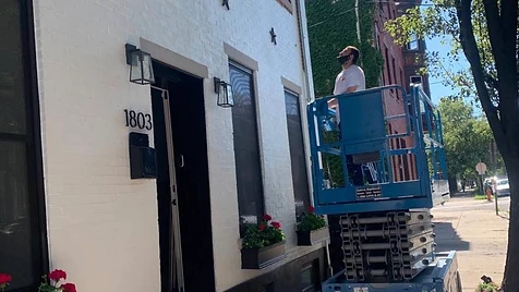 Row House Facade — Scissor-lift access lets us paint the upper facade of a Philadelphia row house safely while the street level stays protected.