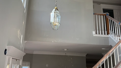 Stairway & Entryway Refresh — A two-story stairway wall rolled in a soft greige — trim taped and banister protected for razor-sharp lines.