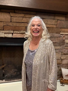 January Jones in a silver sequin cardigan by the fireplace