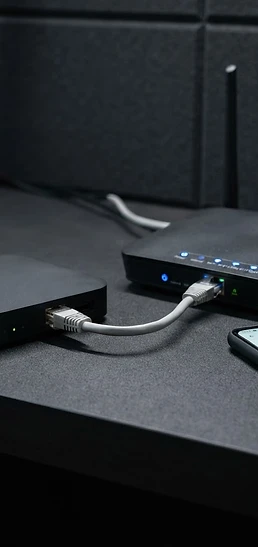 An Android TV box connected to a router with an Ethernet cable, with a smartphone showing network settings