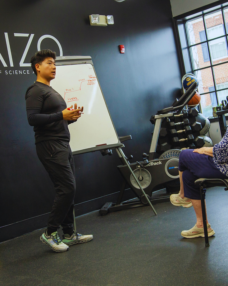 Migma Tamang coaching a client through a session plan on a whiteboard in the studio.