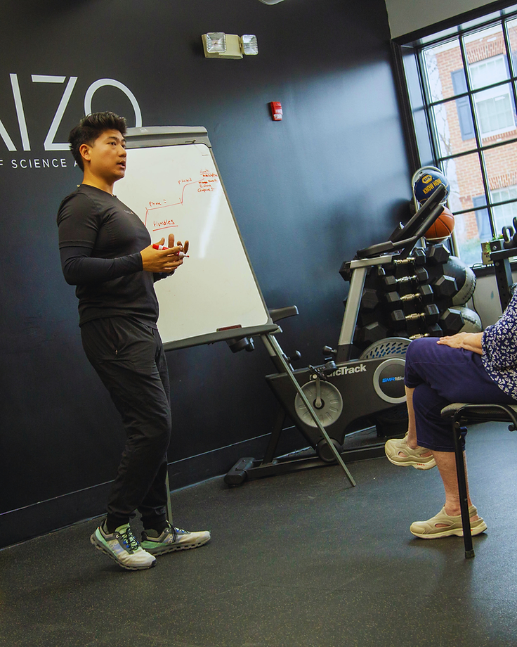 Migma Tamang coaching a client through a session plan on a whiteboard in the studio.