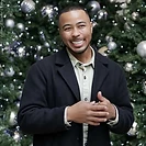 Man smiling in front of a decorated Christmas tree