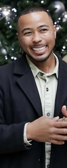 Man smiling in front of a decorated Christmas tree
