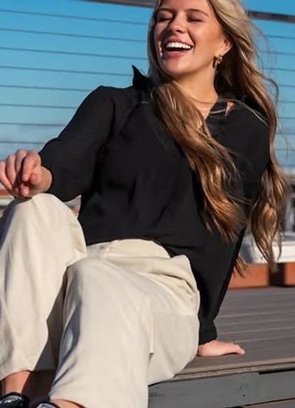 Woman laughing on a wooden deck in late afternoon sun