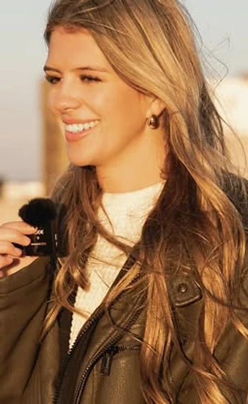Woman holding a lavalier microphone in golden-hour light