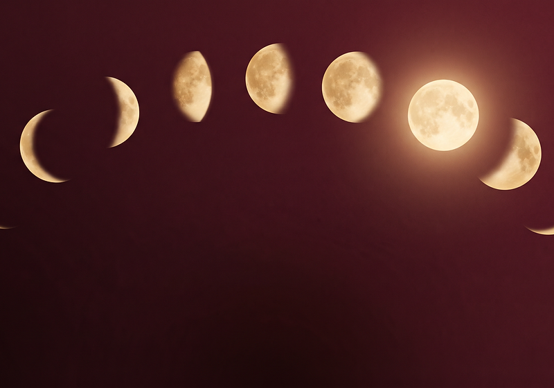 Nine moon phases arcing across a deep burgundy sky