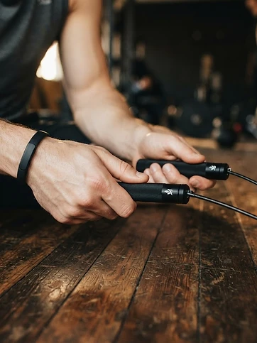 Close-up of hands gripping a jump rope over a gym floor