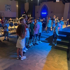 Long line of children under blue stage lighting