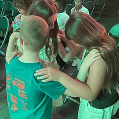 Girl resting hands on a boy's shoulders under green stage light
