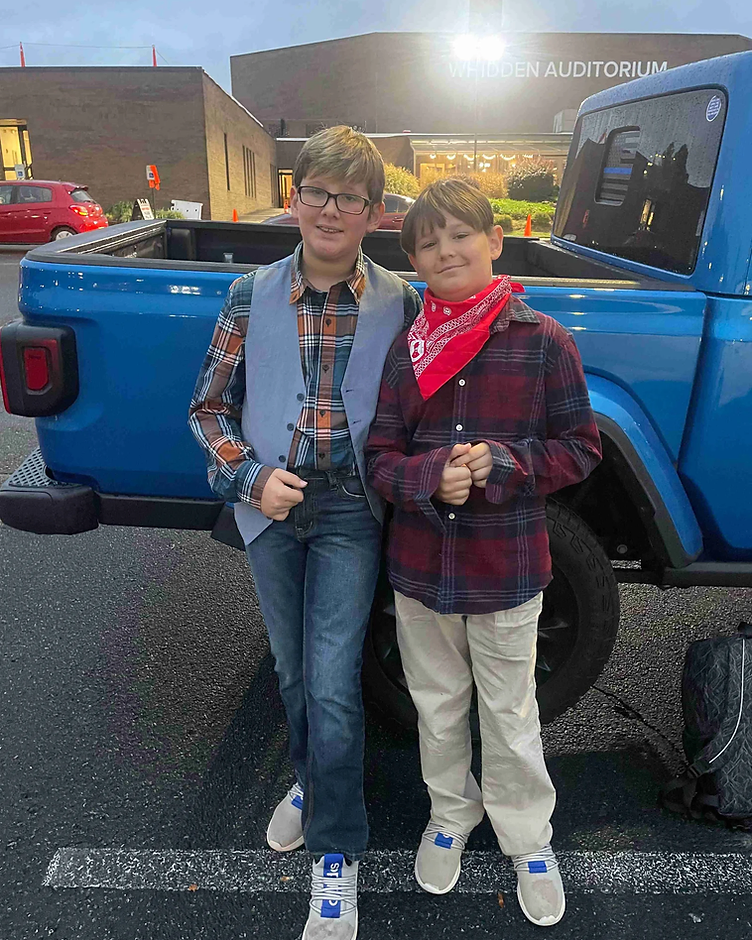 Ezra and Zayden smiling together by a blue truck