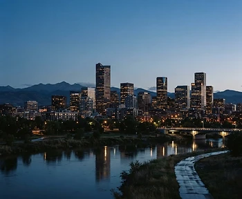Denver skyline at dusk with the Rocky Mountain front range rising behind the city