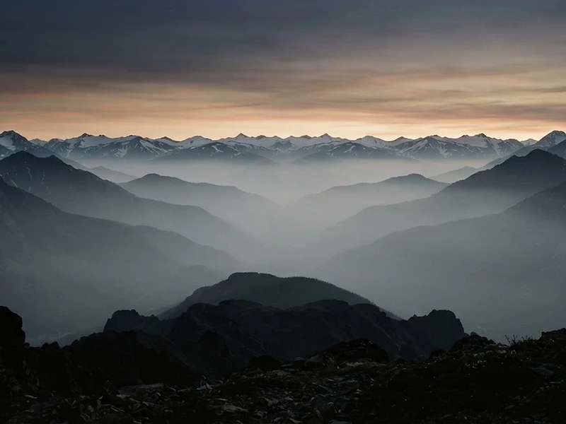 Mountain ridge meeting a coastal horizon at dusk, representing Denver and San Diego