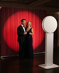 Guests posing in front of the photo booth and a custom event backdrop