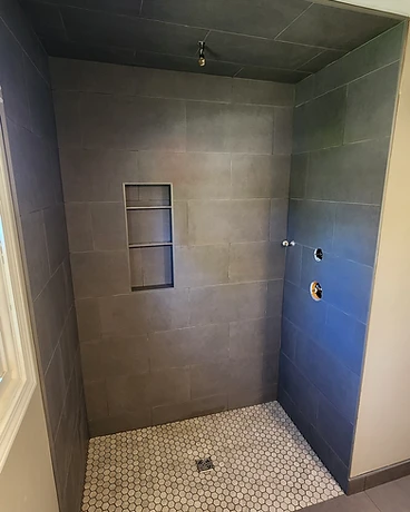 Curbless tile shower with dark grey walls and a hex mosaic floor