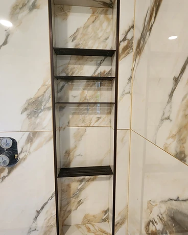Recessed shower niche with veined tile and a dark metal frame