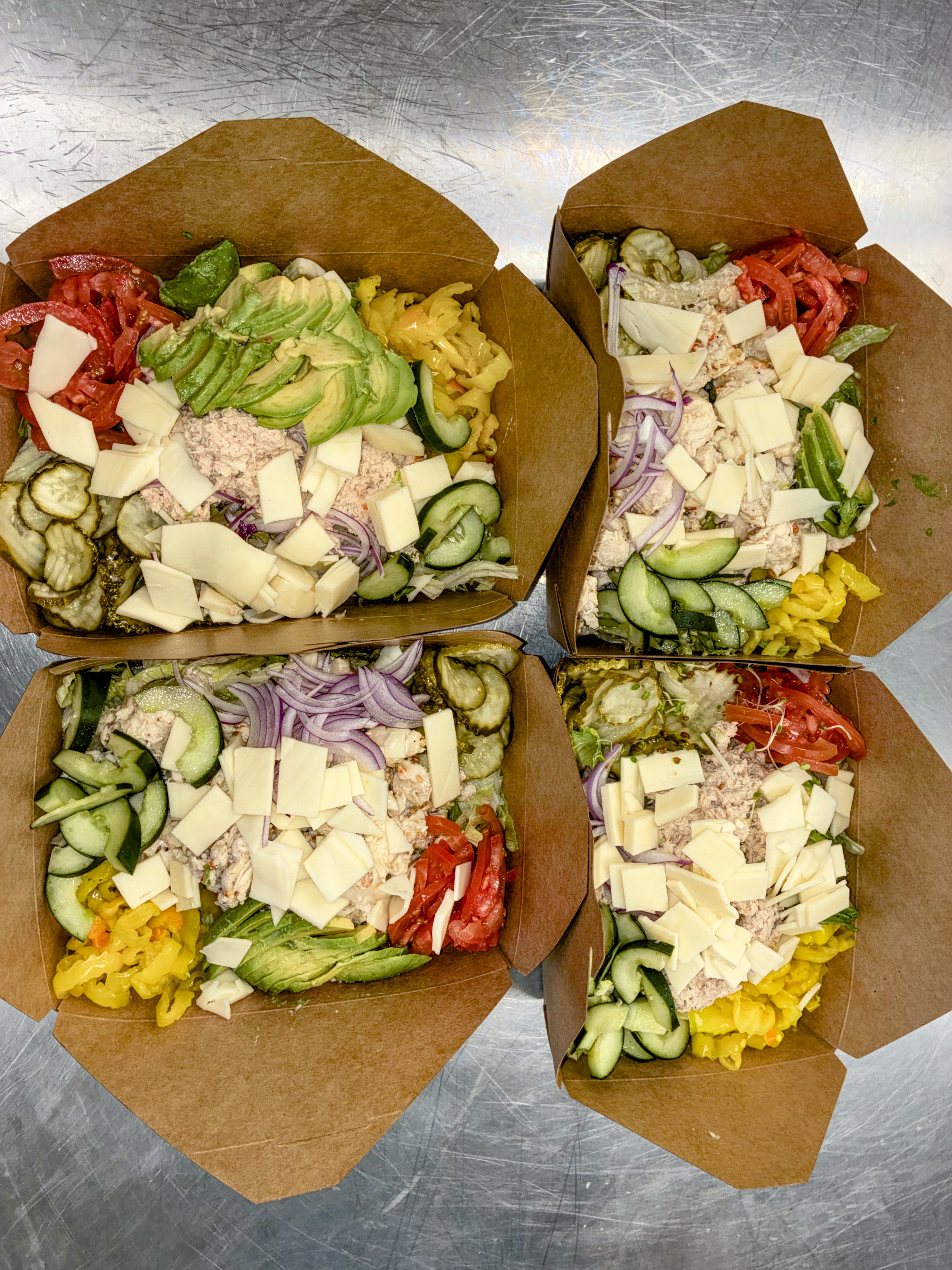 Four kraft boxes of fresh chopped salads with avocado, tomato and cheese