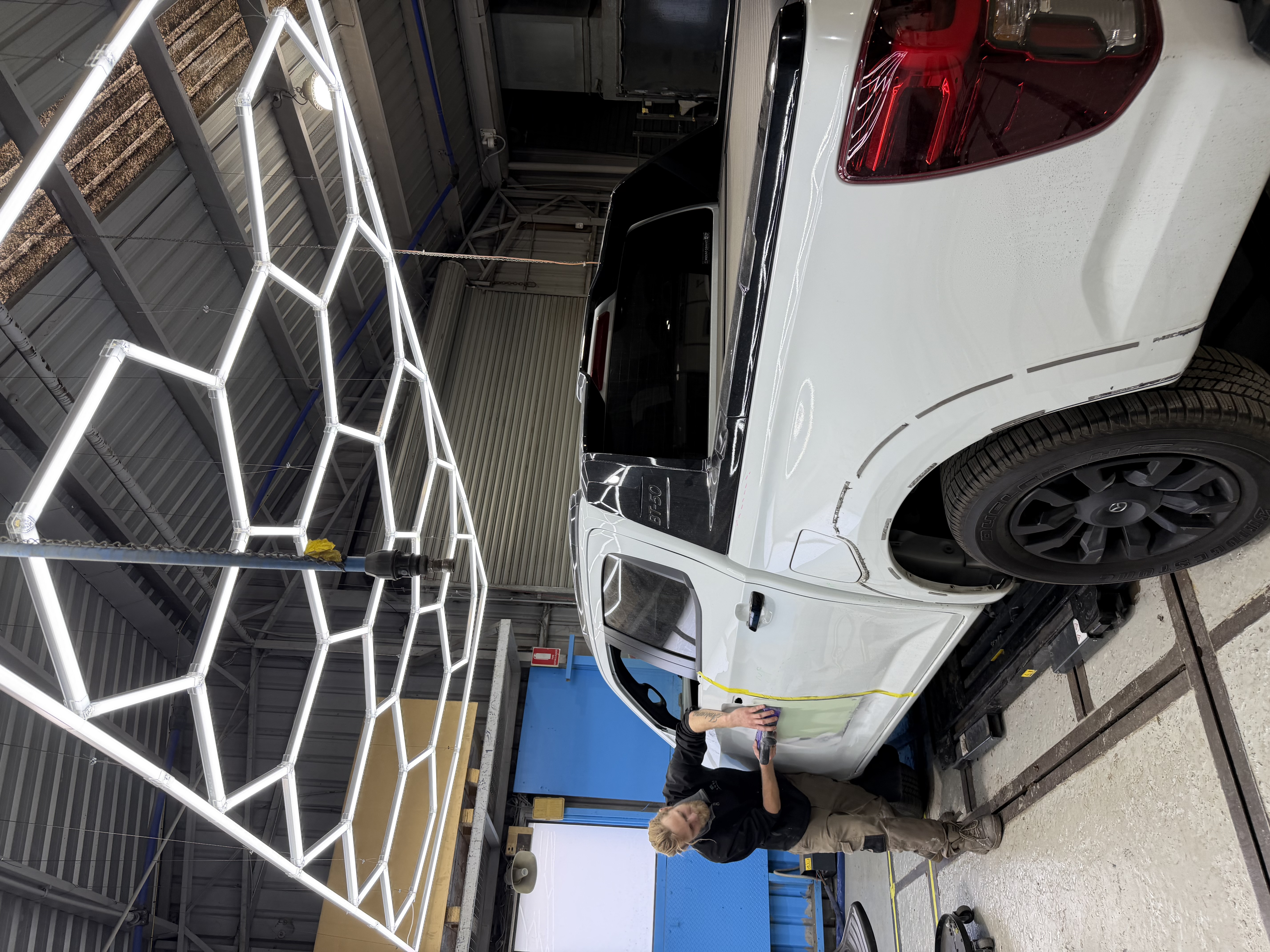 HS Autobody technician sanding a vehicle door in the workshop