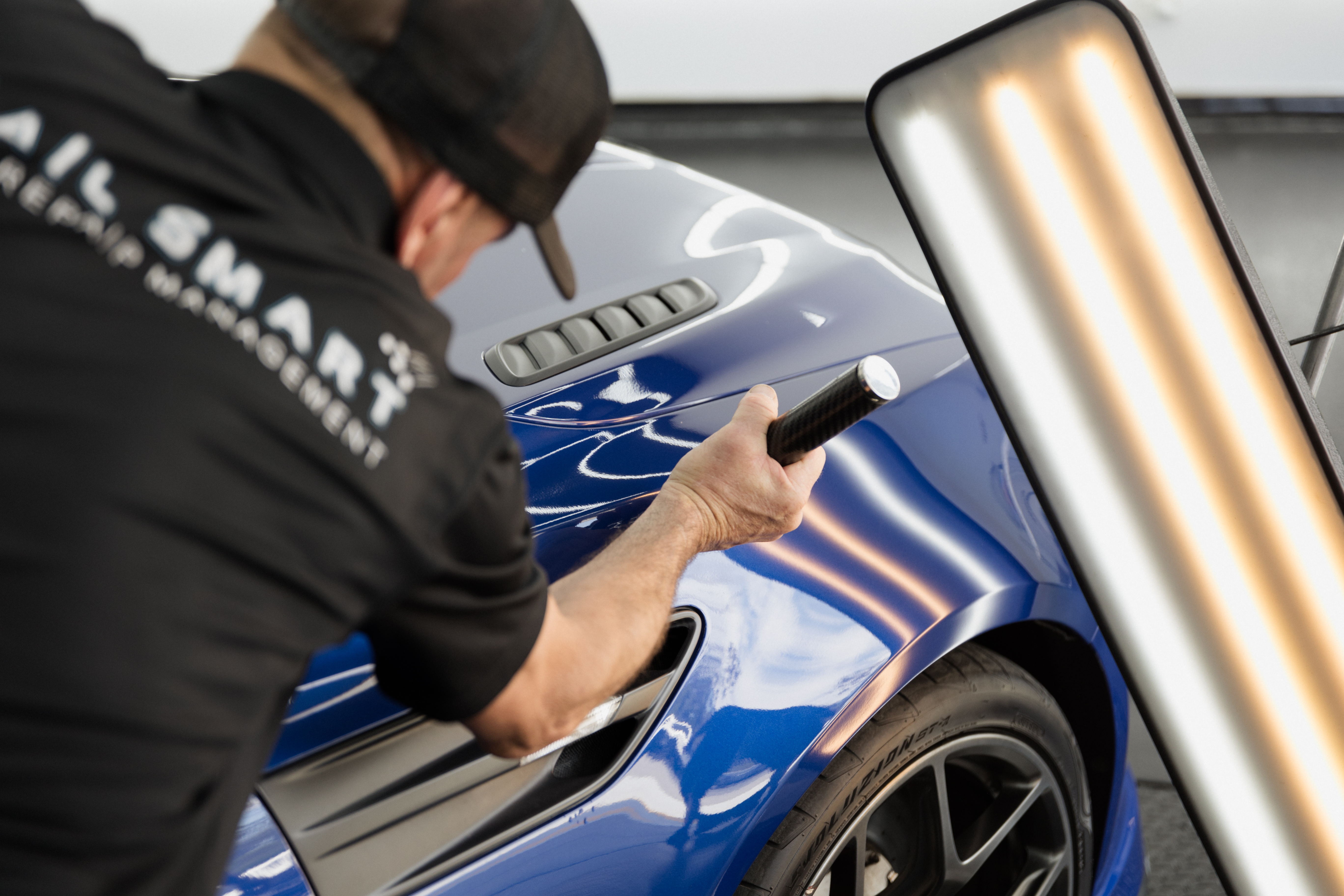 HS Autobody technician repairing a blue car panel