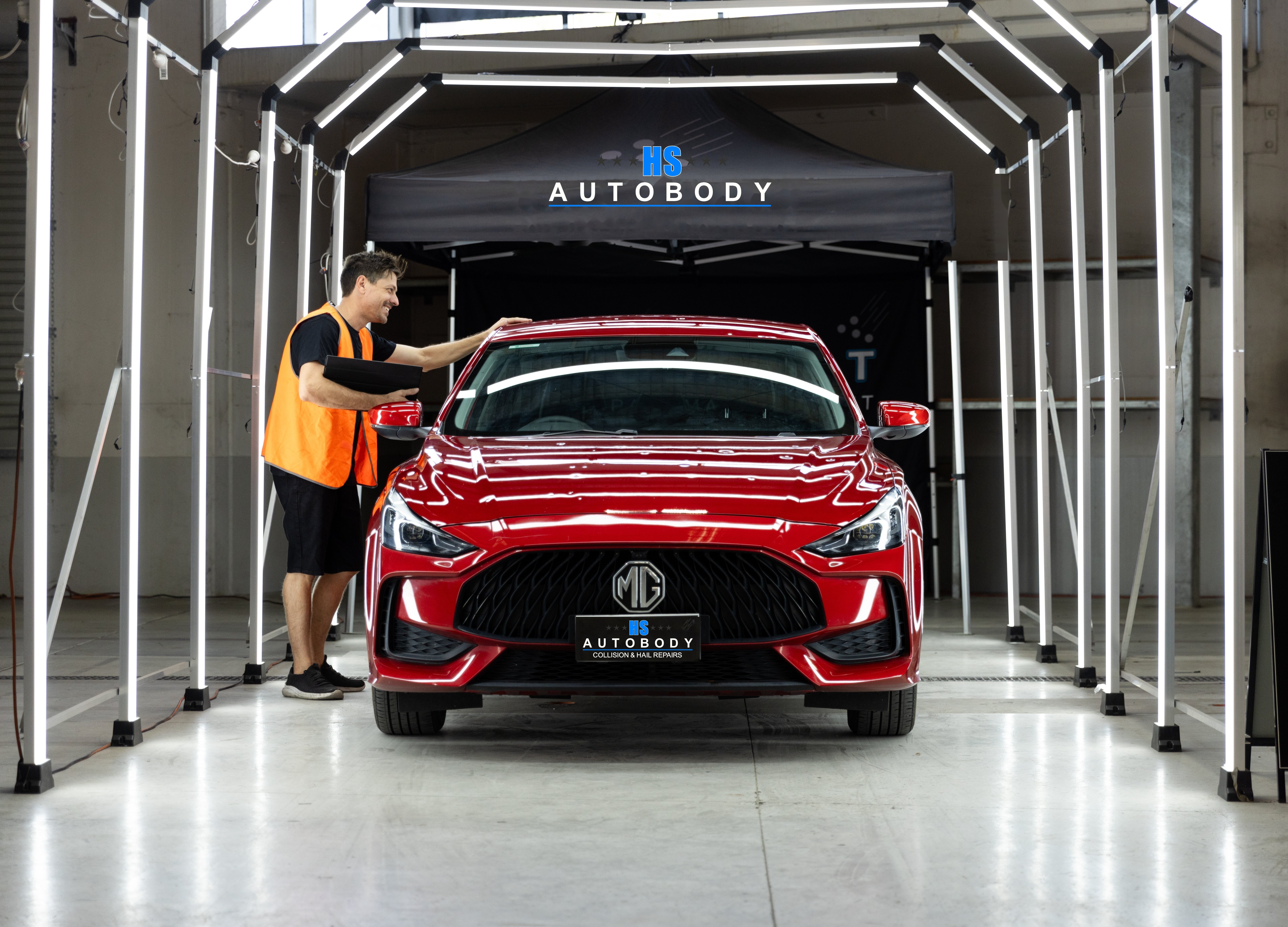 HS Autobody technician inspecting a vehicle in the diagnostic lighting tunnel