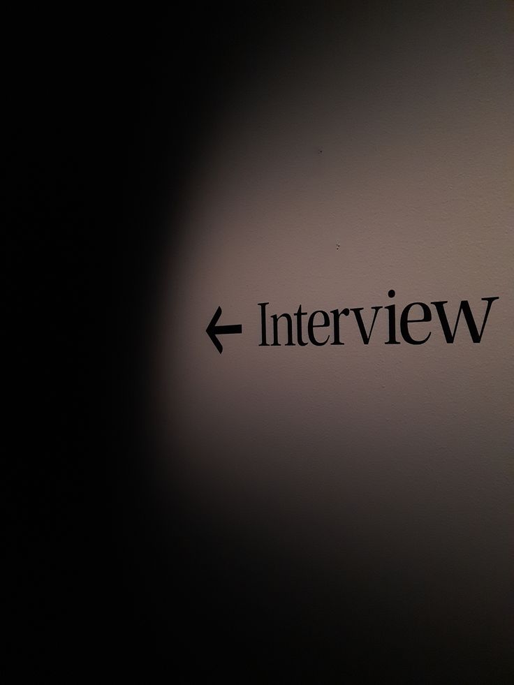 Interview-Schild mit Pfeil an der Wand, Chiaroscuro-Beleuchtung