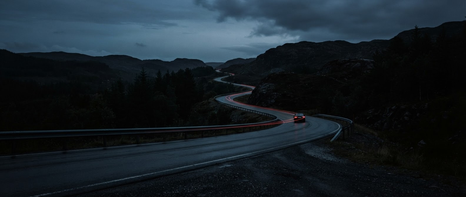 A lonely curving road at dusk with subtle red taillight blur stretching into the distance