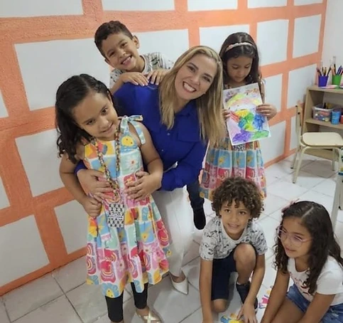 Profissional do Instituto Jordana Bombeiro abraçando criança durante atividade em grupo