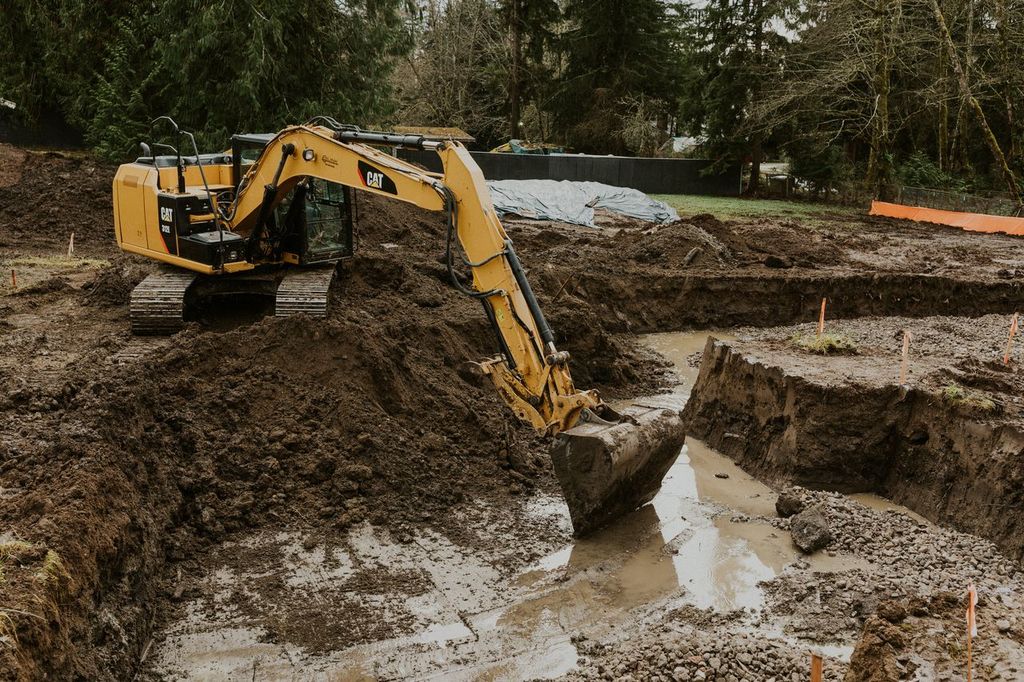 Caterpillar excavator digging in mud on a wooded job site