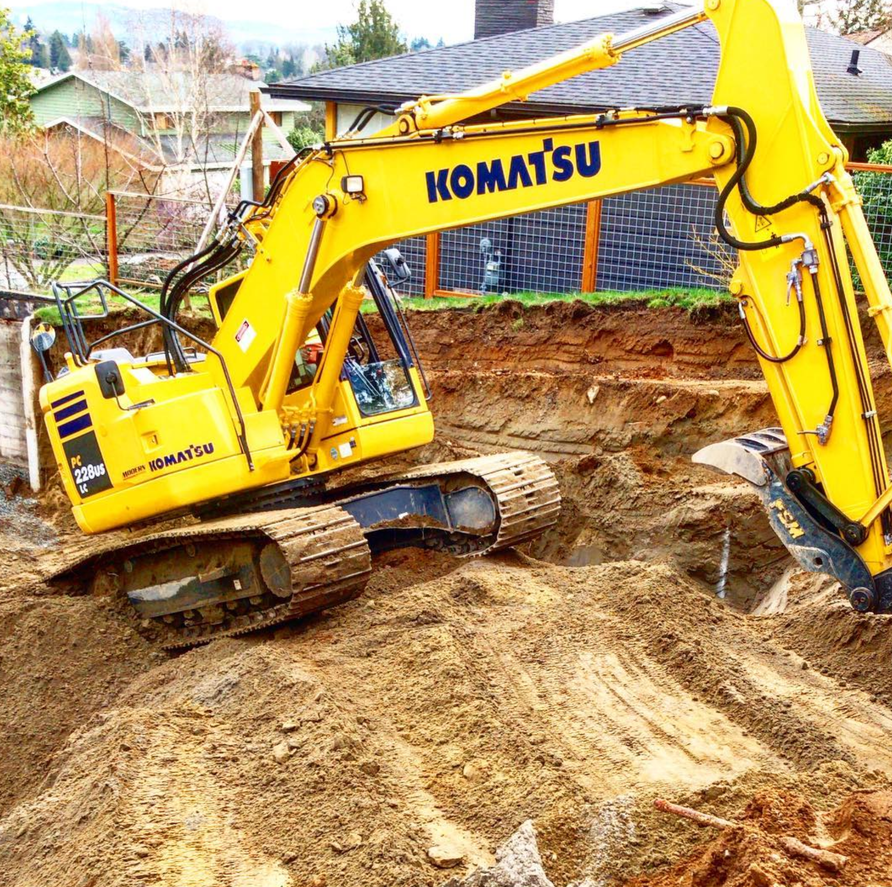 Komatsu excavator working in a freshly dug trench on a residential site