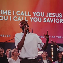 A worship leader singing with hands raised during a past Wave Church gathering