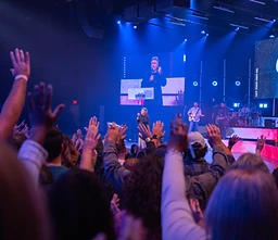 Congregation with hands raised during a past Wave Church gathering