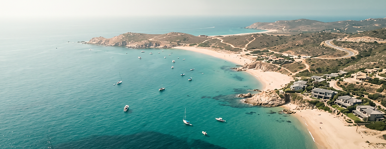 Aerial view of a Mediterranean coastal bay with turquoise water and a crescent sandy beach