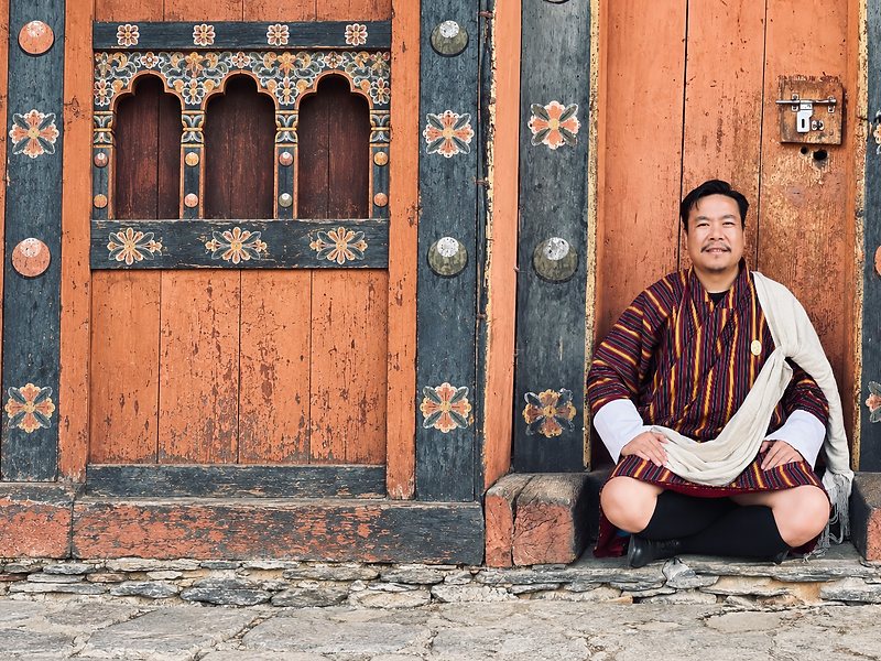 Kinley Rabgyel seated at a painted Bhutanese doorway