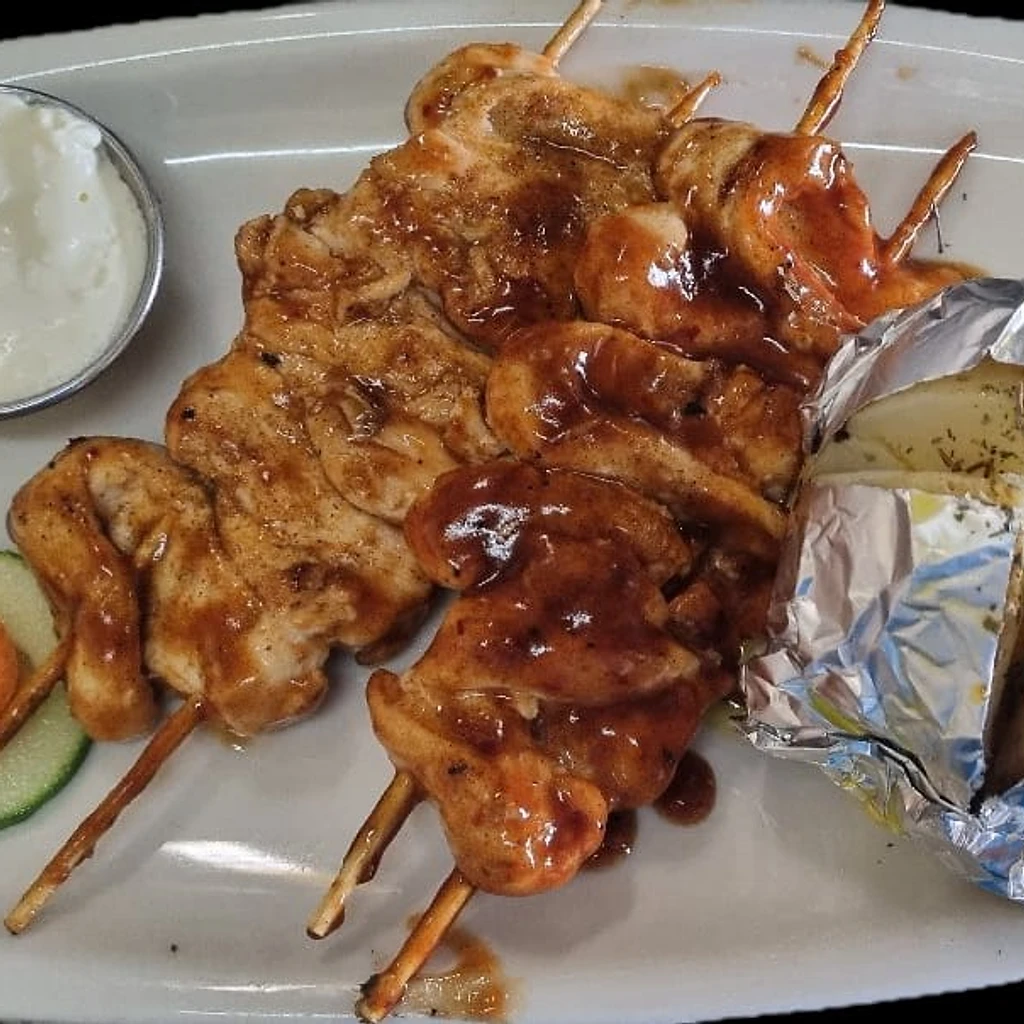Grilled chicken skewers with baked potato and dipping sauce at Ferreira's Sports Bar in Boksburg